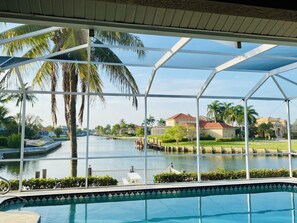 A pool area with a view of a body of water and palm trees.