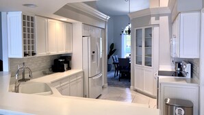 A modern kitchen with white cabinetry, a stainless steel sink, and a built-in dishwasher. - 8 Minute Walk to Beach Luxury 4 Bdrm Waterfront home -salt water heated Pool (Marco Island)