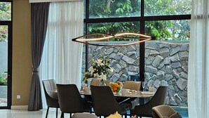 Un área de comedor moderna con una pared de piedra, una mesa de comedor con sillas y un amplio ventanal con cortinas.