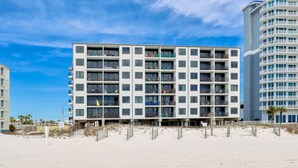 Ein modernes Hotel mit mehreren Etagen, Balkonen und Blick auf den Strand.