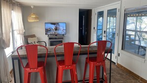 Eine Küche mit Fernseher, roten Barhocker und Blick ins Freie.