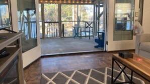 Ein Zimmer mit einer Schiebeglastür, die auf eine Außenpatio mit Lichterkette, Tisch und Stühlen führt.