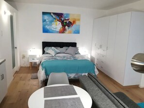 A bedroom with a bed, bedside tables, a desk, a wardrobe, and a painting on the wall.