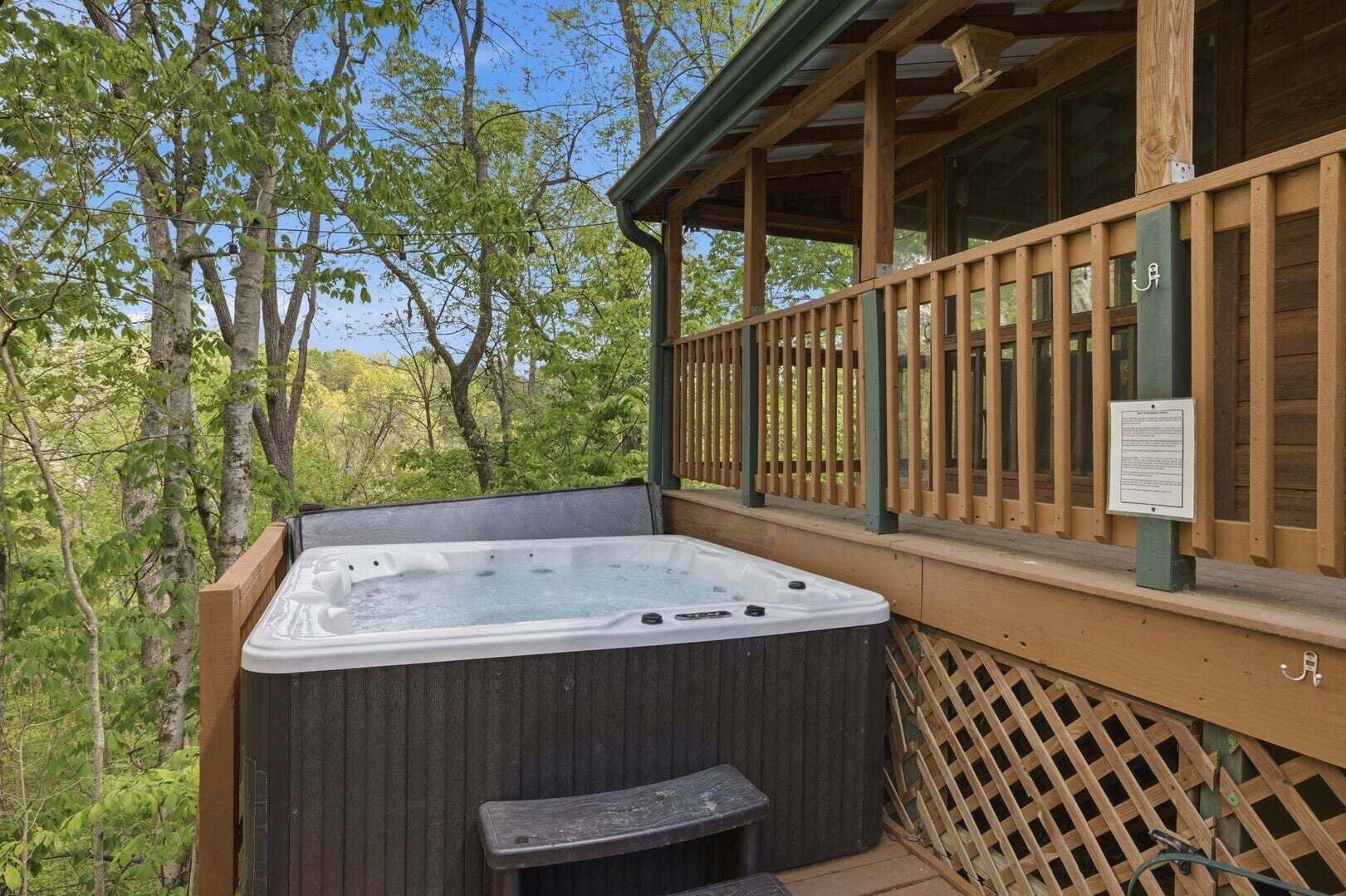 Een hottub op een terras buiten, met een houten leuning en omheining.