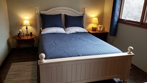 A neatly arranged bedroom with a bed, two bedside tables, and a window with curtains.