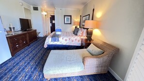 A hotel room with a bed, a sofa, a TV, a desk, and a lamp. - Kauai Beach Resort, Top Floor, Pool View (Kauai)