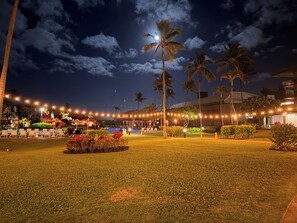 A nighttime outdoor area with palm trees, string lights, and a pool. - Kauai Beach Resort, Top Floor, Pool View (Kauai)