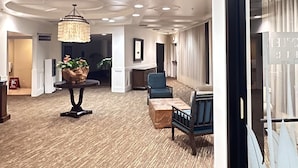 A spacious lobby with a 'BUSINESS CENTER' sign, a chandelier, and seating areas. - Kauai Beach Resort, Top Floor, Pool View (Kauai)