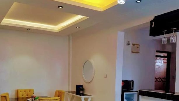 A modern living room with a dining area, a sofa, and a chandelier. - Sandalwood Suites Nakuru (Nakuru)