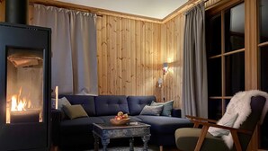 Una sala de estar acogedora con chimenea, un sofá, una mesa de centro y un sillón.