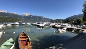 A marina with boats docked, clear water, and mountains in the background.