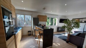 A modern kitchen with a central island, wooden cabinets, and a dining area with bar stools.