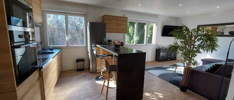 A modern kitchen with a central island, wooden cabinets, and a dining area with bar stools.