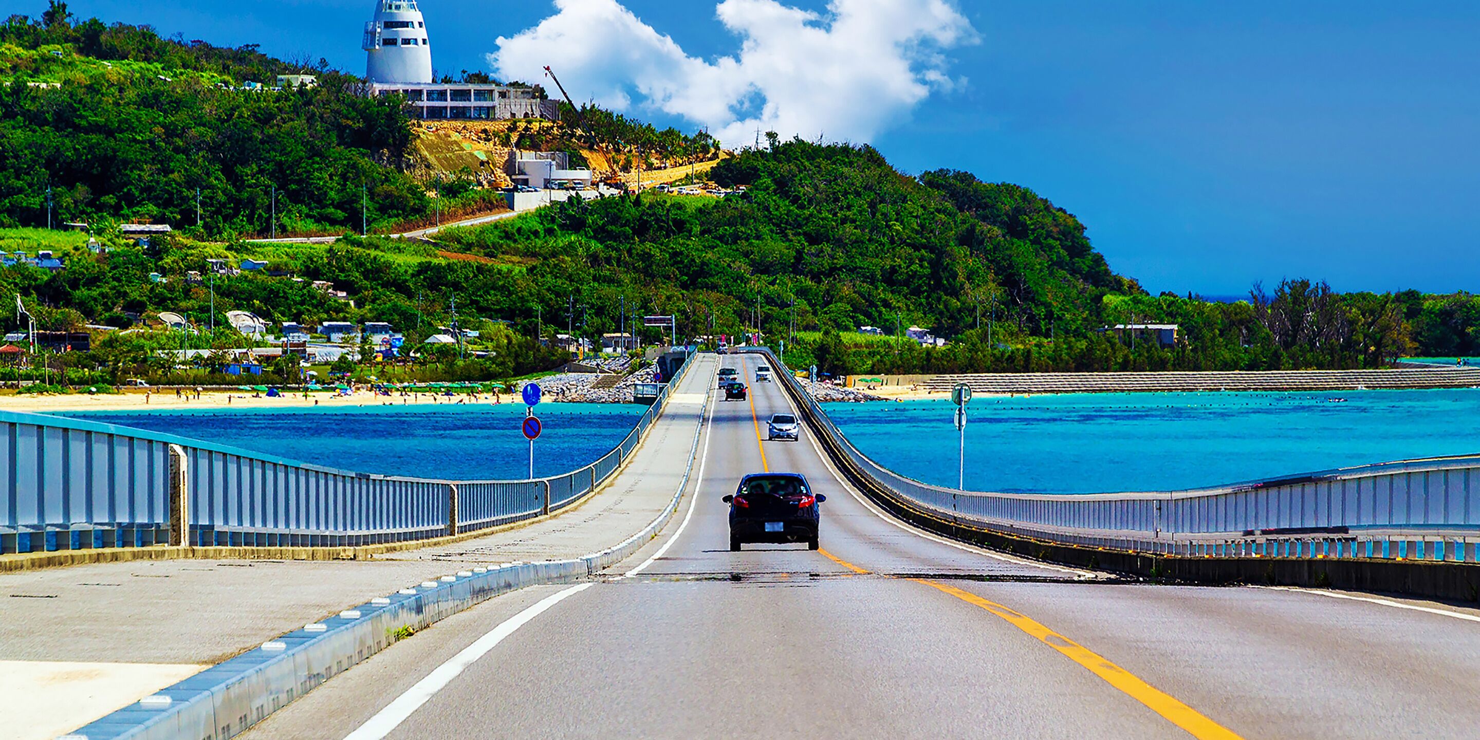 A coastal road with a bridge leading to a beach.