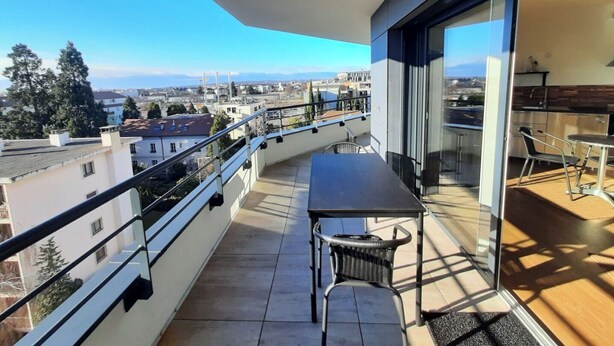 Ein Balkon mit Tisch und Stühlen und Blick auf die Stadt.