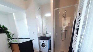 Ein kleines Badezimmer mit Toilette, Waschmaschine und Dusche.