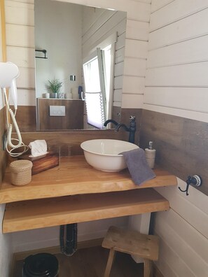 A bathroom with a wooden vanity, a white sink, a towel, a tissue box, and a hairdryer. - Cozy vacation home for 4 people (Oberdorla)