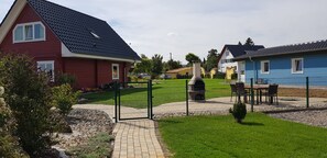 A residential area with houses, a barbecue grill, and a fenced patio. - Cozy vacation home for 4 people (Oberdorla)