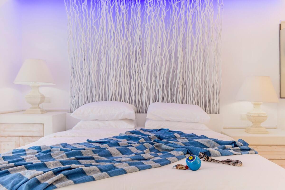 A neatly made bed with a blue and gray checkered blanket, white pillows, and a blue decorative item on the bed.