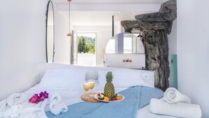 A hotel room with a bed, a wooden headboard, a mirror, and a view of the outdoors. - Kouros Home and Suites (Rhodes)