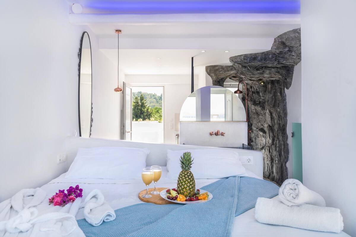 A hotel room with a bed, a wooden headboard, a mirror, and a view of the outdoors.
