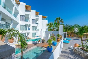 A modern hotel with a pool area, outdoor seating, and potted plants. - Kouros Home and Suites (Rhodes)