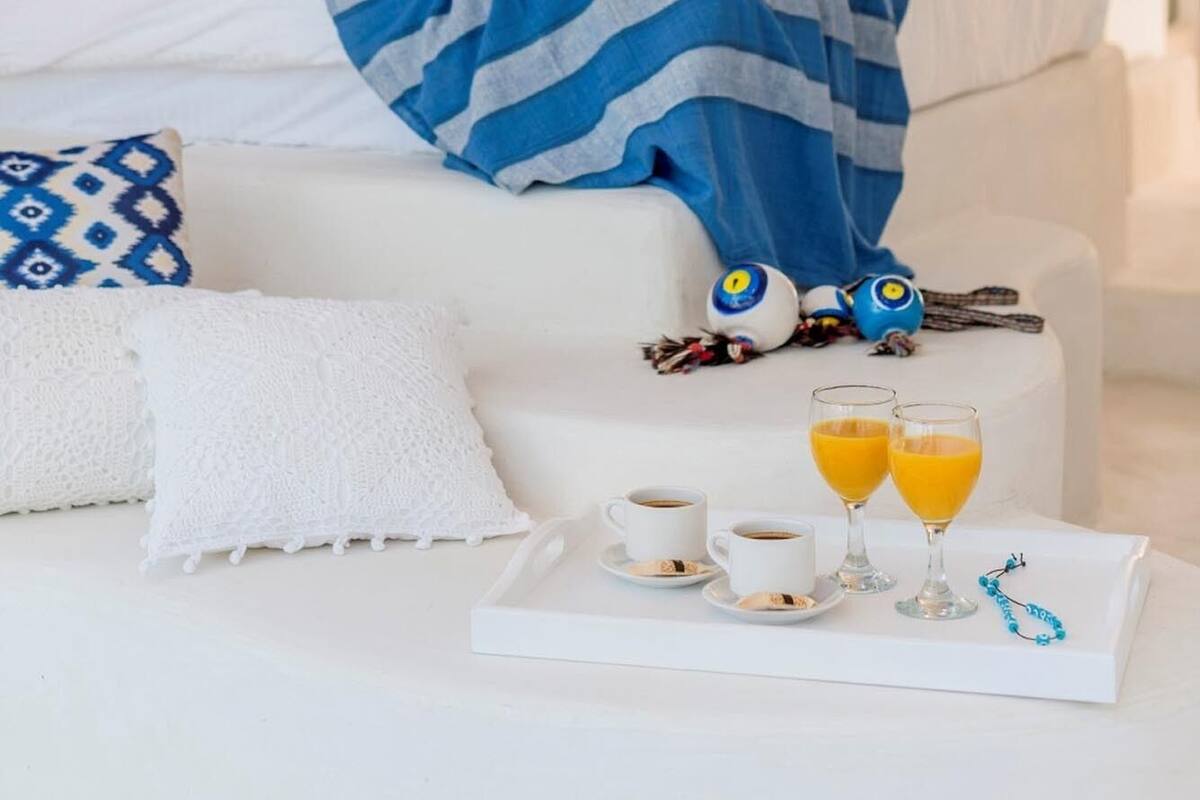 A modern bedroom with a bed, bedside table, and a tray with drinks and snacks.