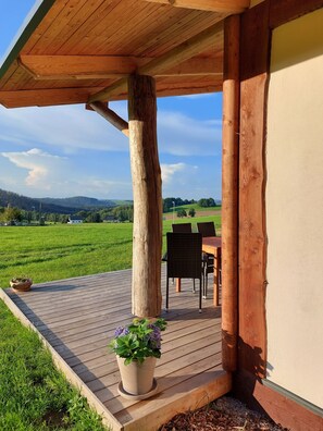 A wooden deck with a potted plant, a table, and chairs. - Cozy newly built vacation home in the heart of the Erzgebirge "Haus West" (Pockau-Lengefeld)