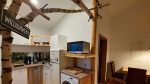 A compact kitchen with a washing machine, a coffee maker, and a microwave.