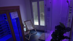 A room with a glass door, a wooden chair, a potted plant, and a small table with items on it. - Hotel a Licorne (Carnac)
