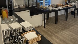 A modern kitchen with a coffee station, breakfast buffet, and a view of the outdoors. - Hotel a Licorne (Carnac)