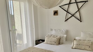 A bedroom with a large bed, a star decoration on the wall, and a hanging light fixture. - Hotel a Licorne (Carnac)
