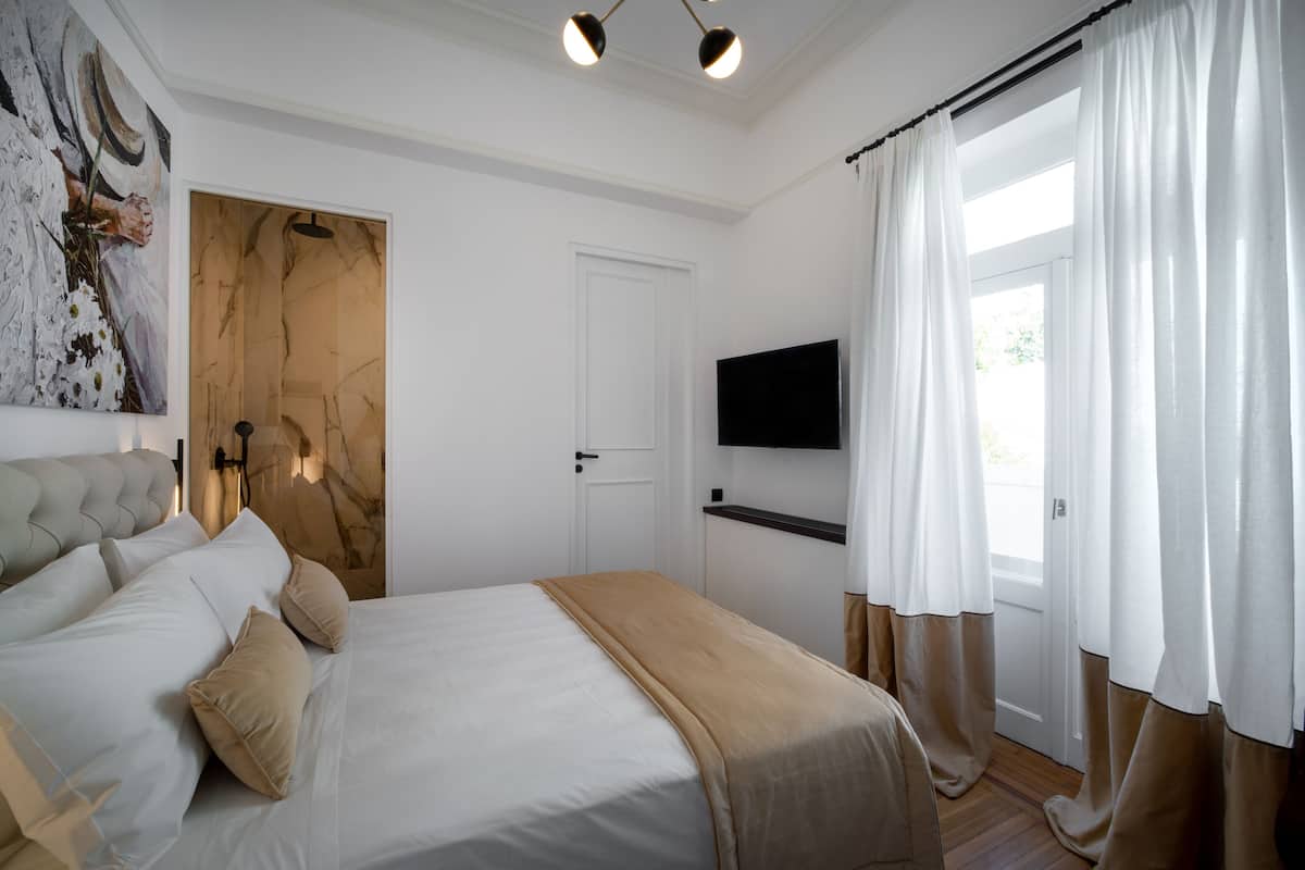 Ein Schlafzimmer mit einem Bett, einem Fernseher an der Wand und einer Tür.