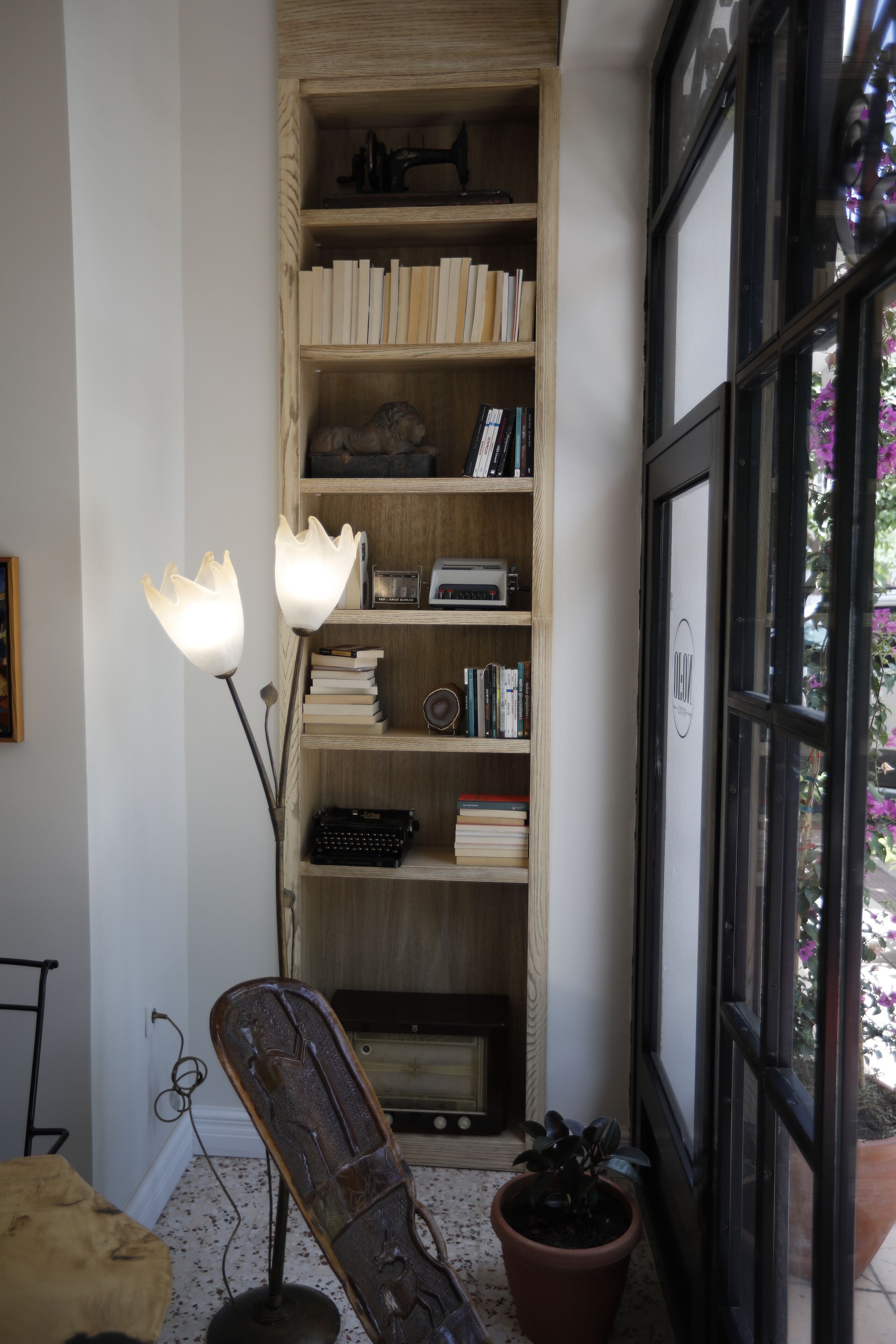 A corner with a wooden bookshelf, a vintage typewriter, and a potted plant.