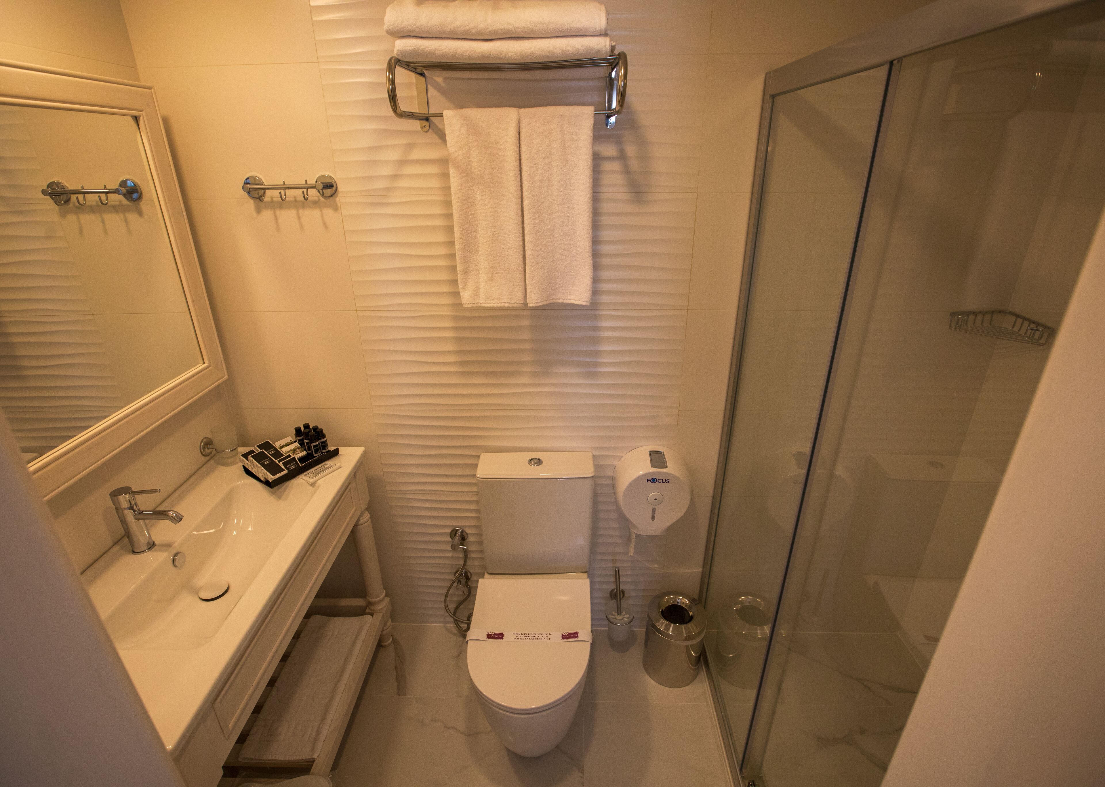 A bathroom with a toilet, sink, and glass shower enclosure.