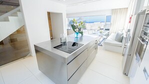 A modern kitchen with a central island, a dining area with a view, and a living space with a sofa and a TV. - Protaras holiday villa - rentprivatevillas 100 (Protaras)