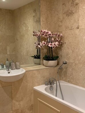 A bathroom with a sink, mirror, potted plants, and a bathtub. - Cheerful 2-bed Cottage With 2 Free Parking, Leeds (Leeds)