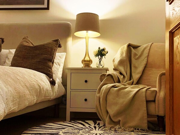 A bedroom with a bed, a nightstand with a lamp, a chair, and a rug. - Cheerful 2-bed Cottage With 2 Free Parking, Leeds (Leeds)