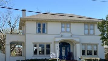 A two-story building with a central entrance, large windows, and a sign indicating a bed and breakfast.