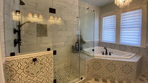 A modern bathroom with a glass-enclosed shower, a freestanding bathtub, and patterned tiles.