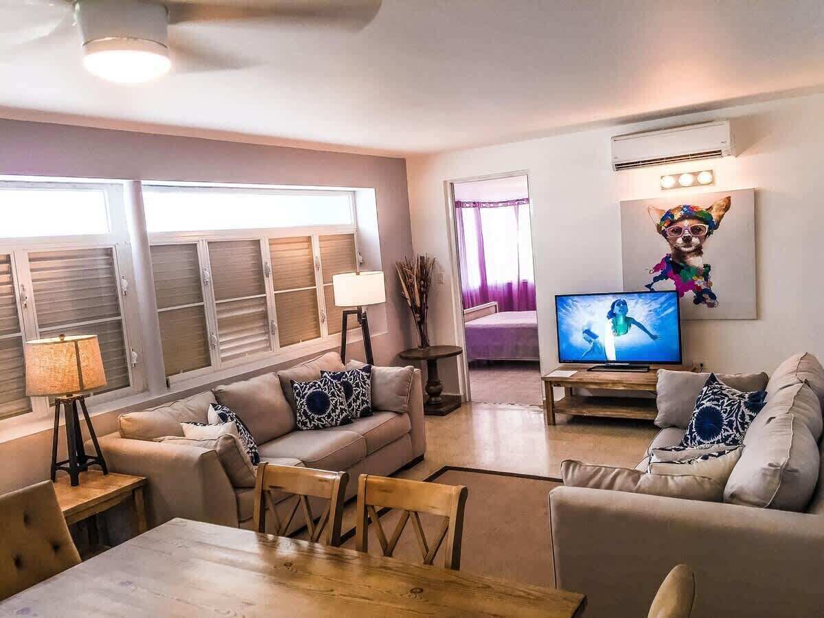 Una sala de estar con un sofá, televisión y un cuadro de un perro.