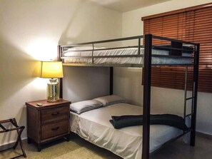 A bunk bed room with a bedside table and lamp.