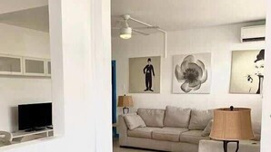 Un saló amb un sofà, una televisió i obres d'art a les parets.