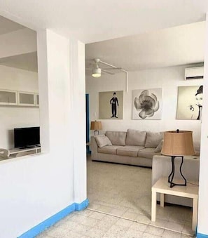 Una sala de estar con sofá, televisión y obras de arte en las paredes.