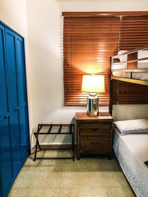 A small, compact room with a bunk bed, a desk with a lamp, and a blue door. - San Juan Gem 7BR-City Views & Onsite Pay Parking! (San Juan)