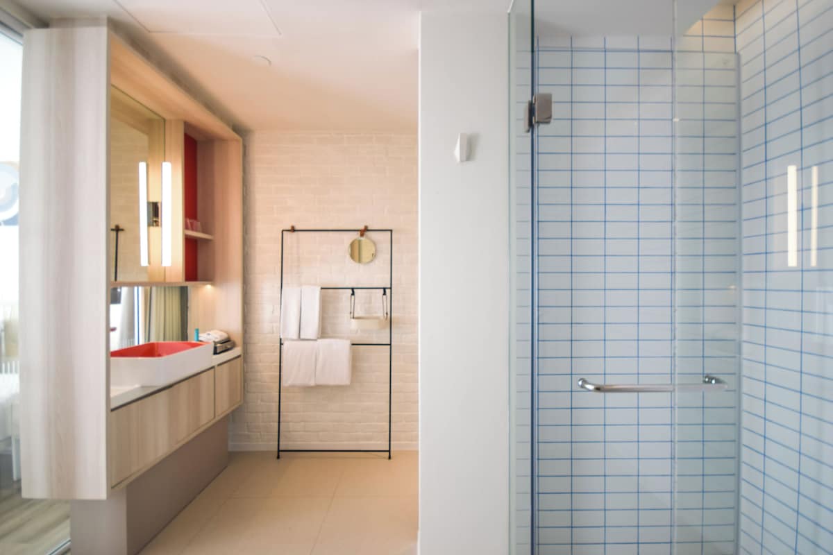 Une salle de bain moderne équipée d’une douche, d’un lavabo et d’un porte-serviettes.