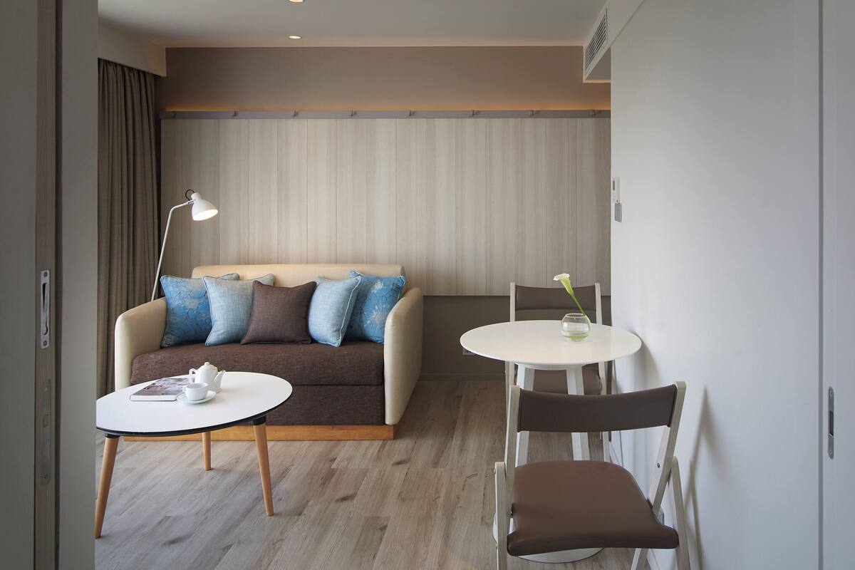 A modern hotel room with a sofa, a small round table, and a chair.