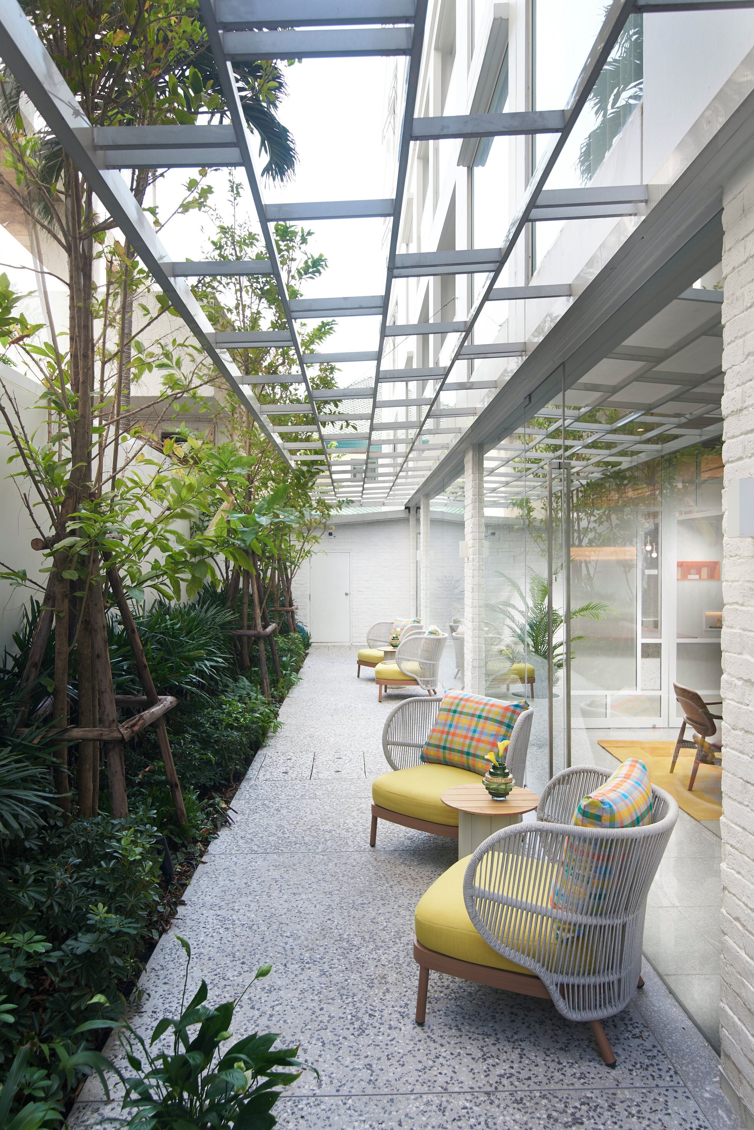 A covered outdoor area with seating, plants, and a glass ceiling.
