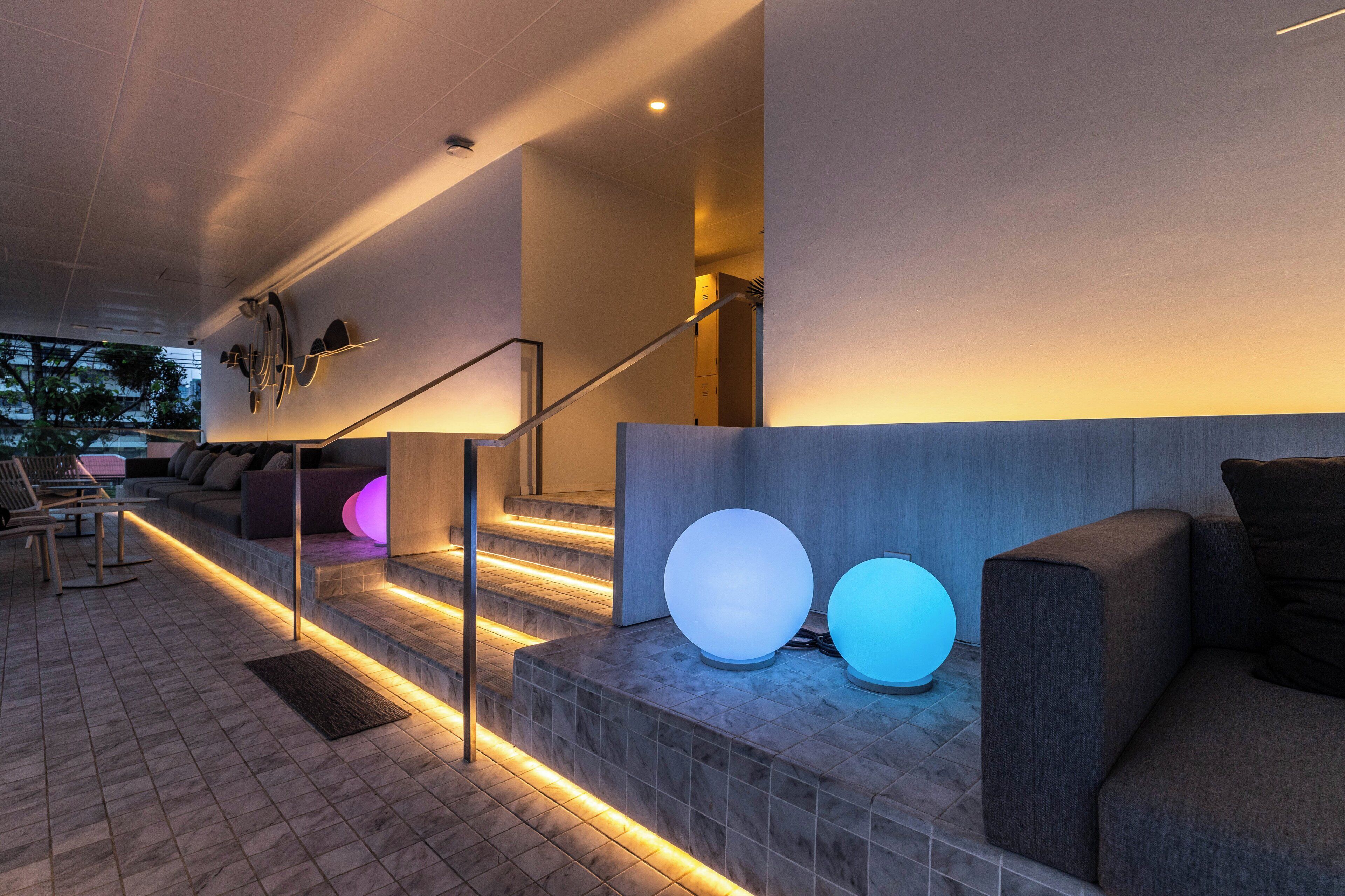 A modern indoor area with a staircase, seating area, and illuminated spherical objects.