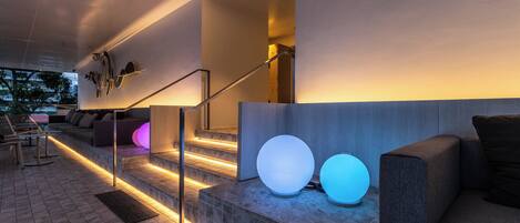 A modern indoor area with a staircase, seating area, and illuminated spherical objects.